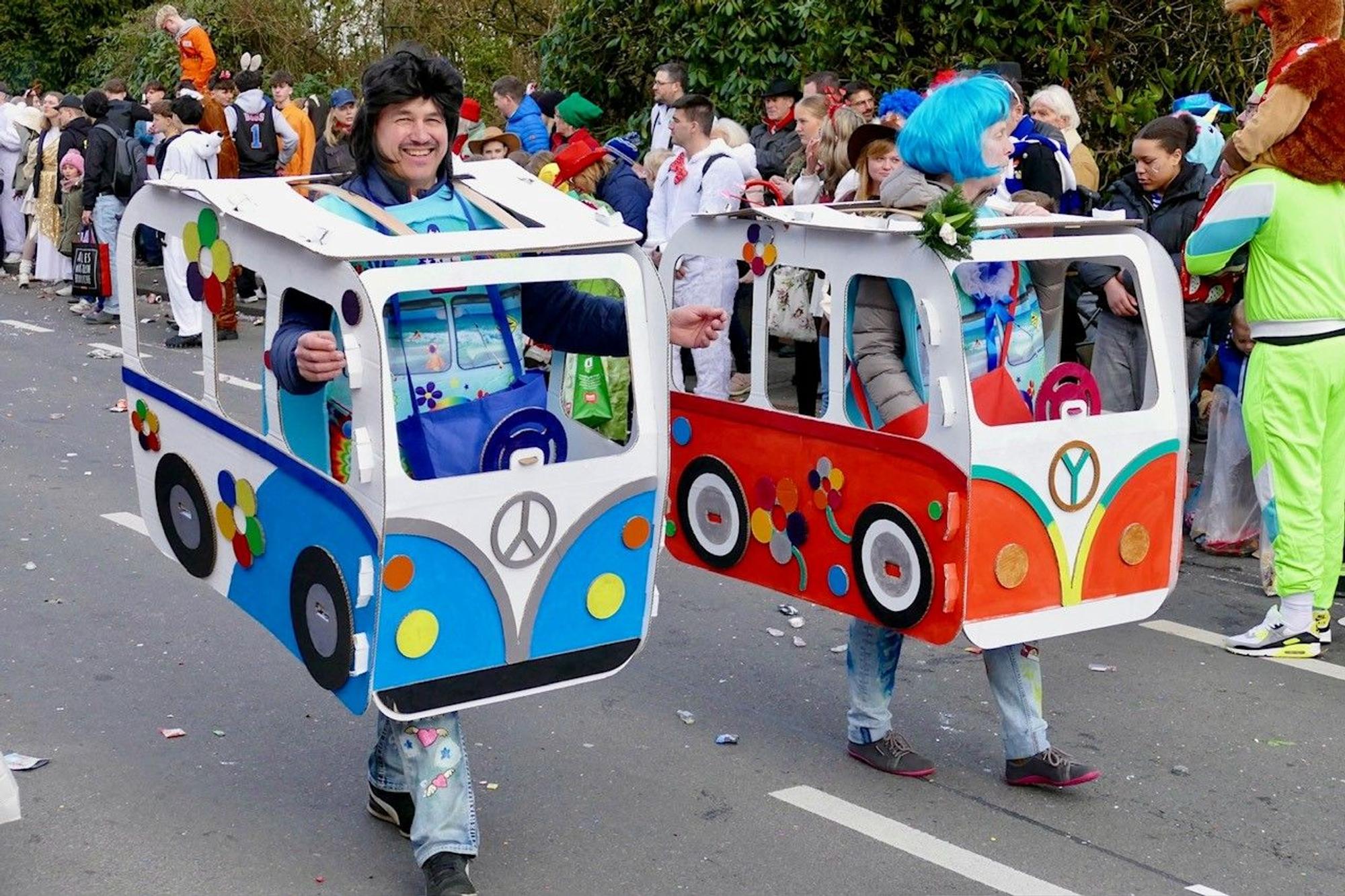 Ein Man und eine Frau tragen gebastelte VW-Busse.