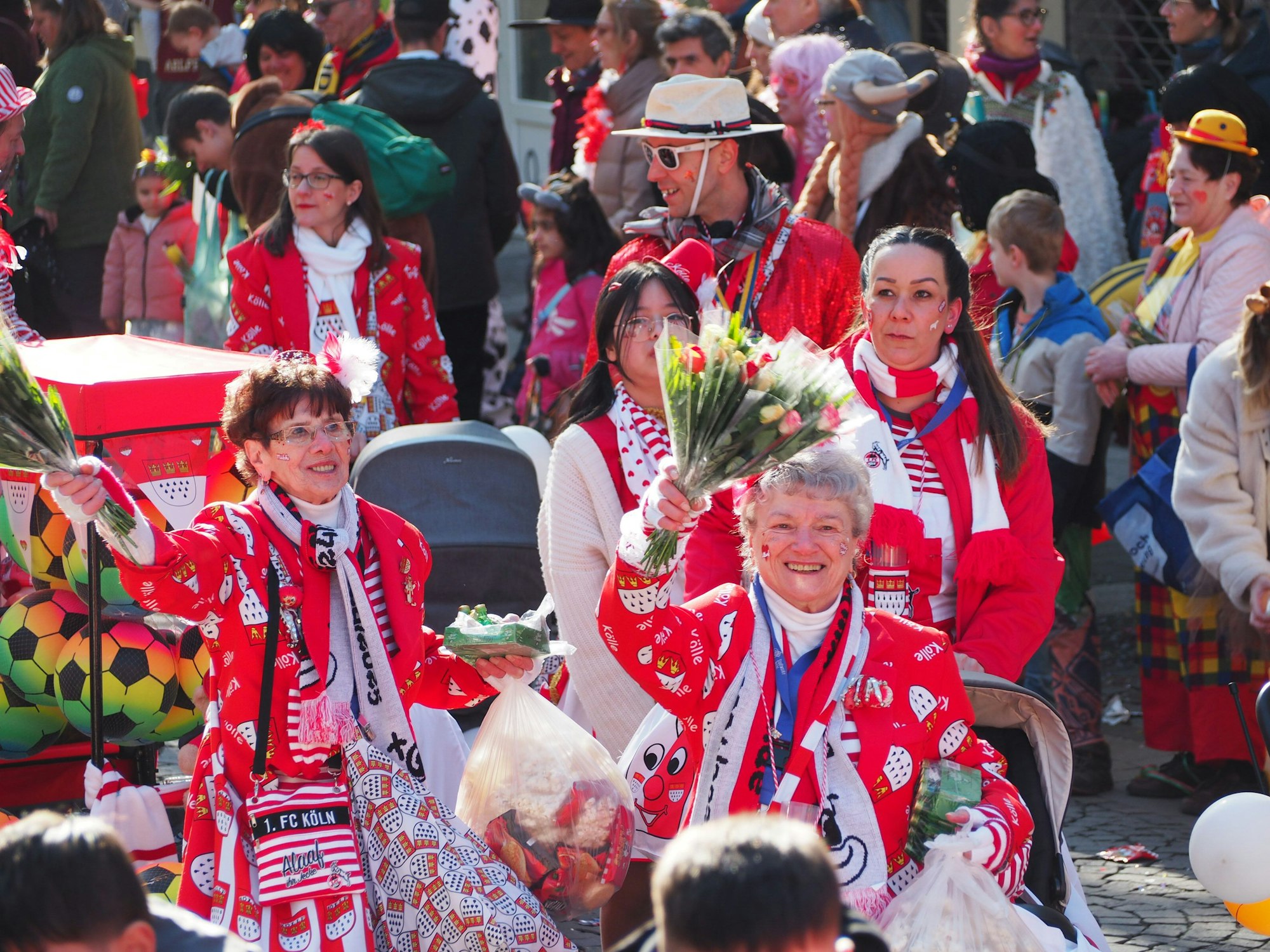 Zwei ältere Frauen winken und lächeln in die Kamera.