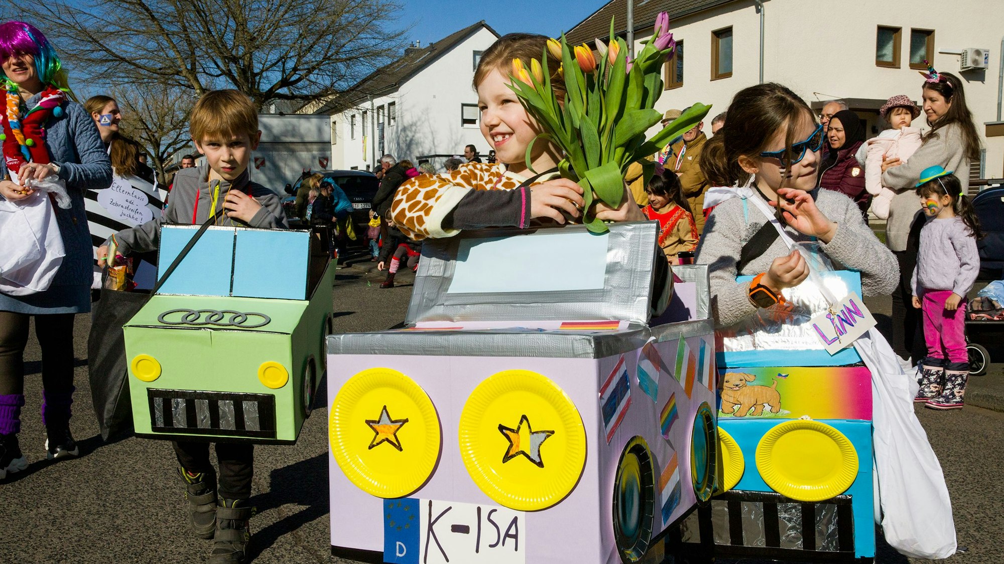 Kinder in Autokostümen verteilen Strüßjer.