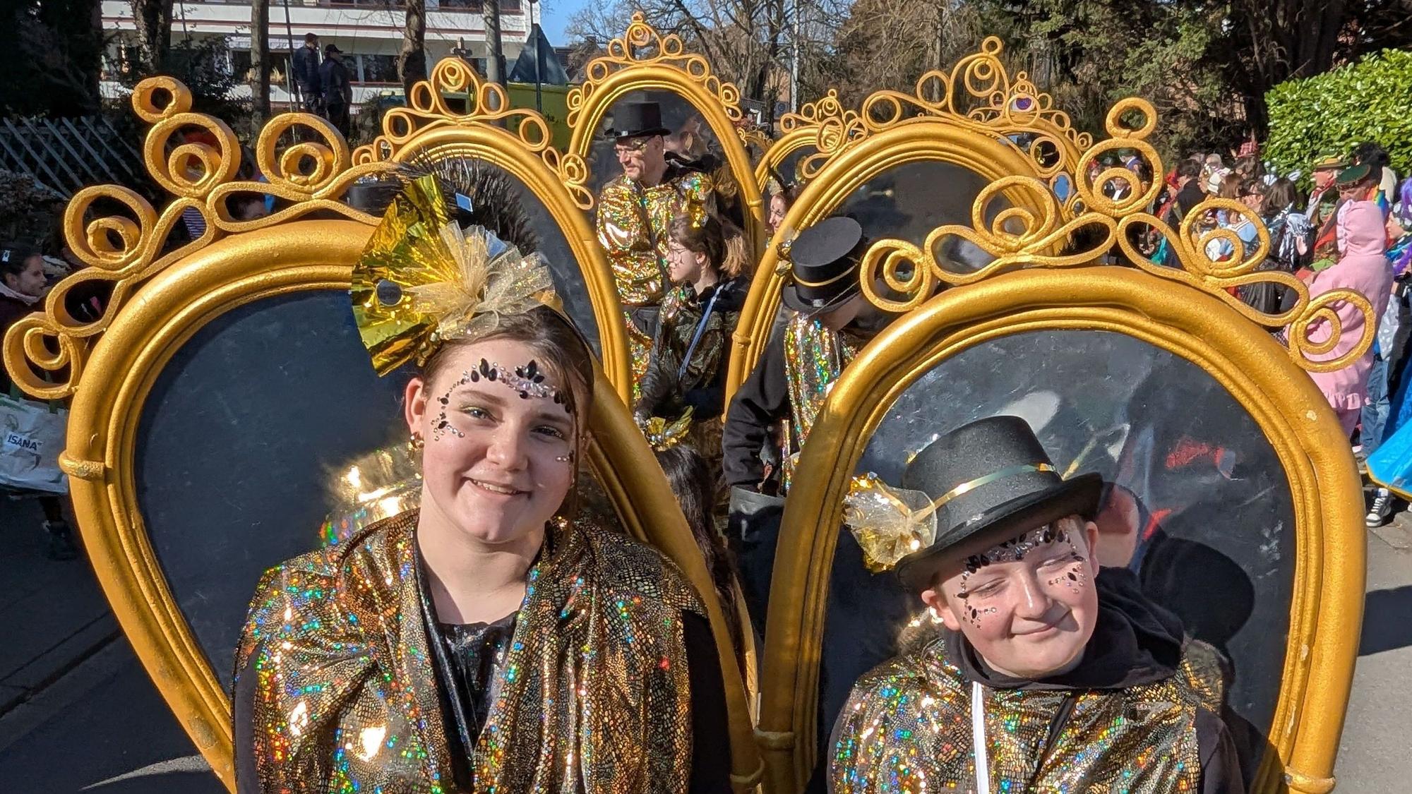 Das Foto zeigt eine Fußgruppe, die große Spiegel auf dem Rücken trägt.