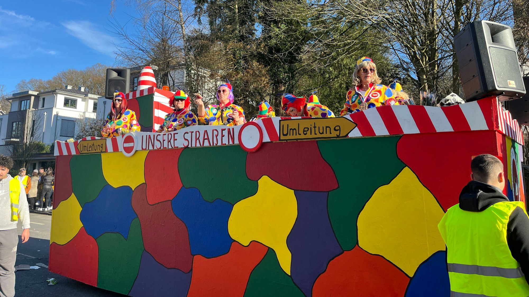 Bunt kostümierte Jecken stehen auf einem Mottowagen.