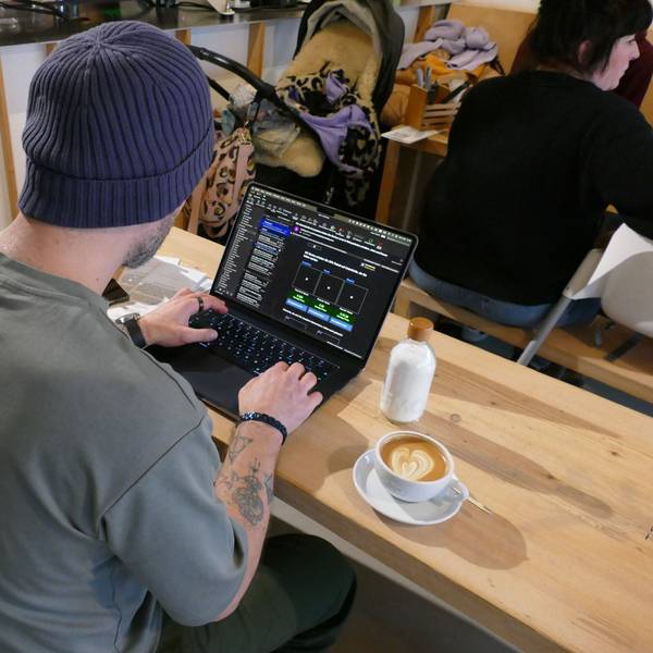 Ein Mann sitzt vor seinem Laptop, neben ihm steht eine Tasse Kaffee.