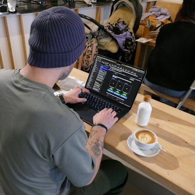 Ein Mann sitzt vor seinem Laptop, neben ihm steht eine Tasse Kaffee.