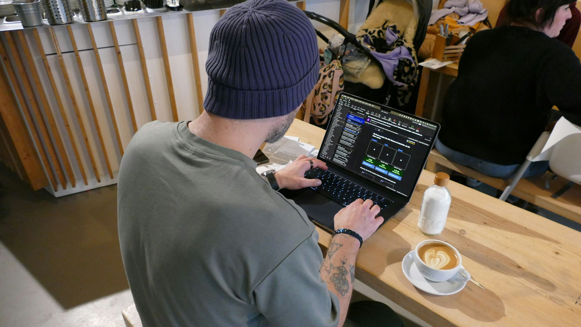 Ein Mann sitzt vor seinem Laptop, neben ihm steht eine Tasse Kaffee.