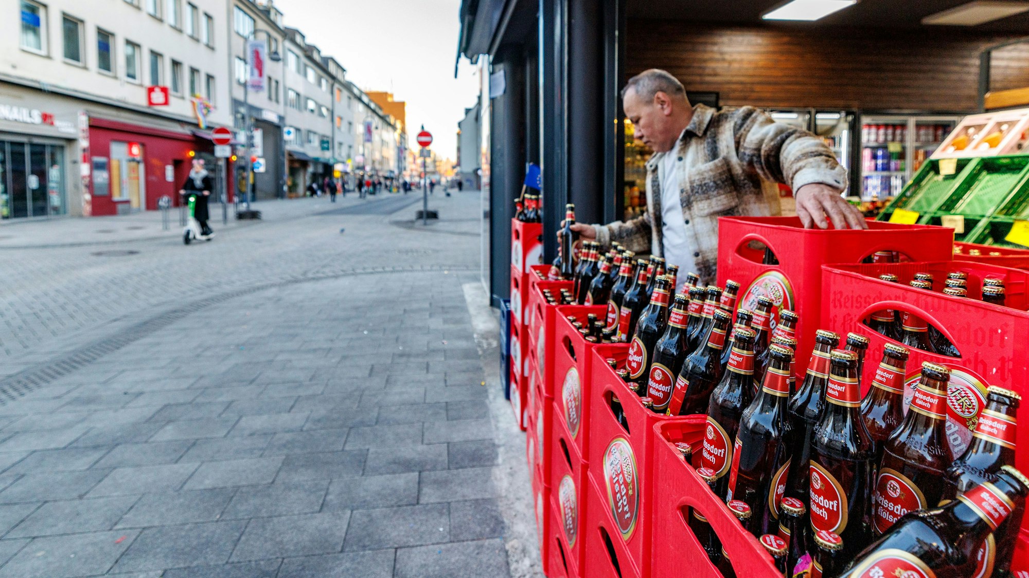 Ein Händler an der Zugstrecke baut am frühen Morgen seine Auslage um, es gibt nur Kölsch.