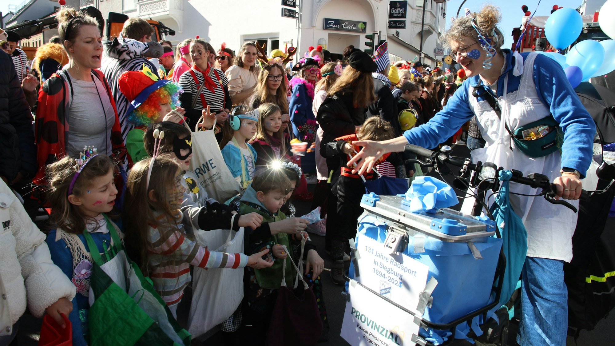 Eine Jecke verteilt Kamelle an Kinder.