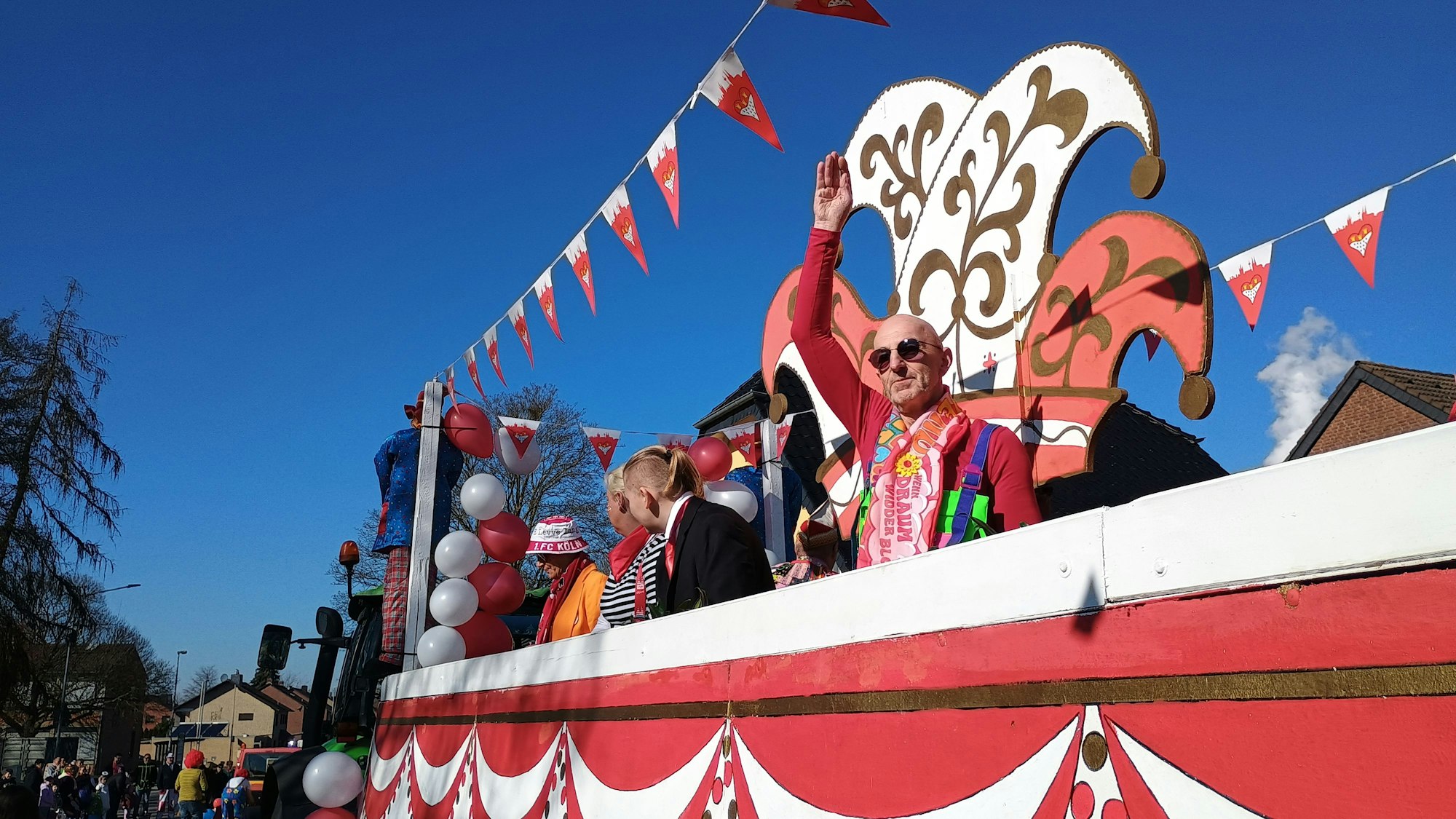 Zu sehen sind einige Mitglieder der Karnevalsfreunde Bedburg-Rath auf ihrem rot-weißen Festwagen.