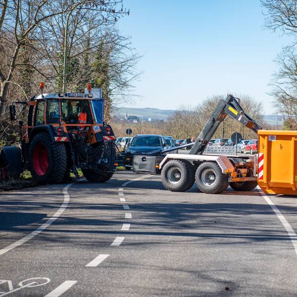 Ein Traktor zieht einen Container quer auf eine Straße.