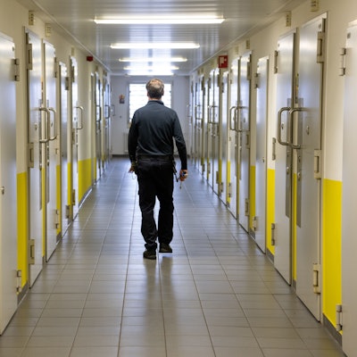 Ein Justizvollzugsbeamter geht durch einen Gang vorbei an den Gefängniszellen. Viele Straftäter kommen in NRW schon schnell in den offenen Vollzug.