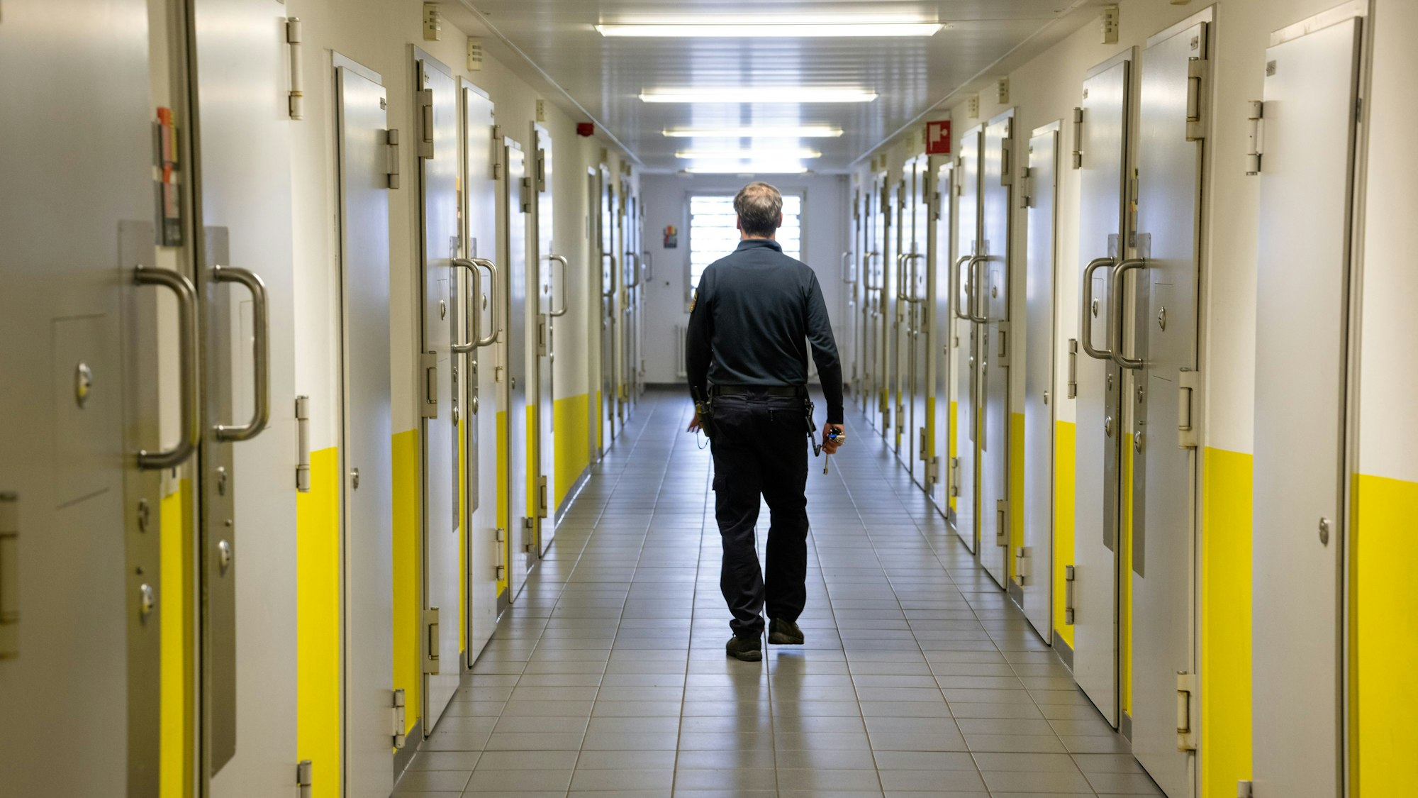 ARCHIV - 16.01.2025, Rheinland-Pfalz, Wittlich: Ein Justizvollzugsbeamter geht durch einen Gang vorbei an den
Gefängniszellen in der Justizvollzugsanstalt (JVA) Wittlich. (zu dpa: «Vierstellige Zahl an Häftlingen kann Bundestag mitwählen») Foto: Harald Tittel/dpa +++ dpa-Bildfunk +++