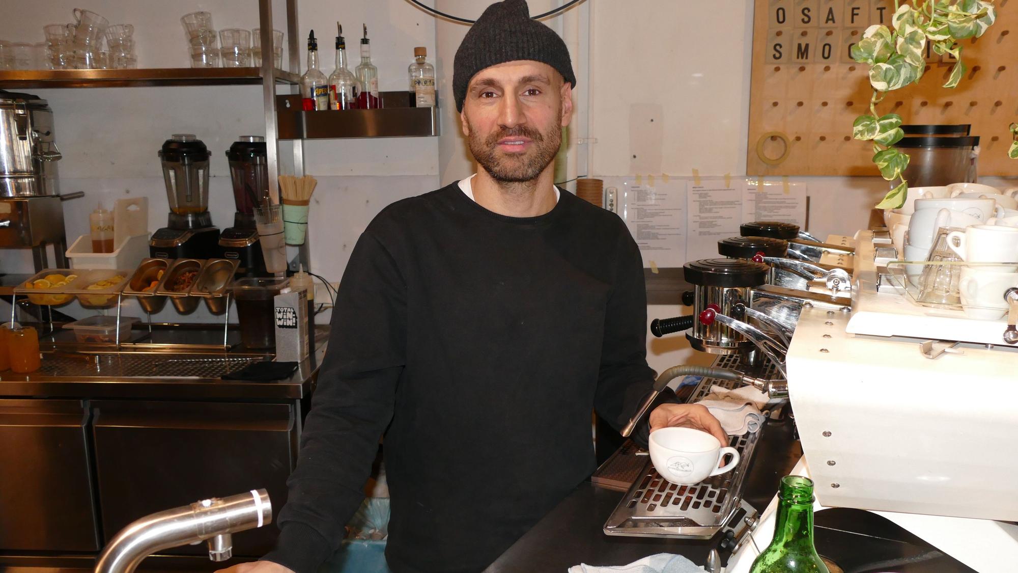 Ein Mann steht an einem Tresen vor einer Kaffeemaschine.