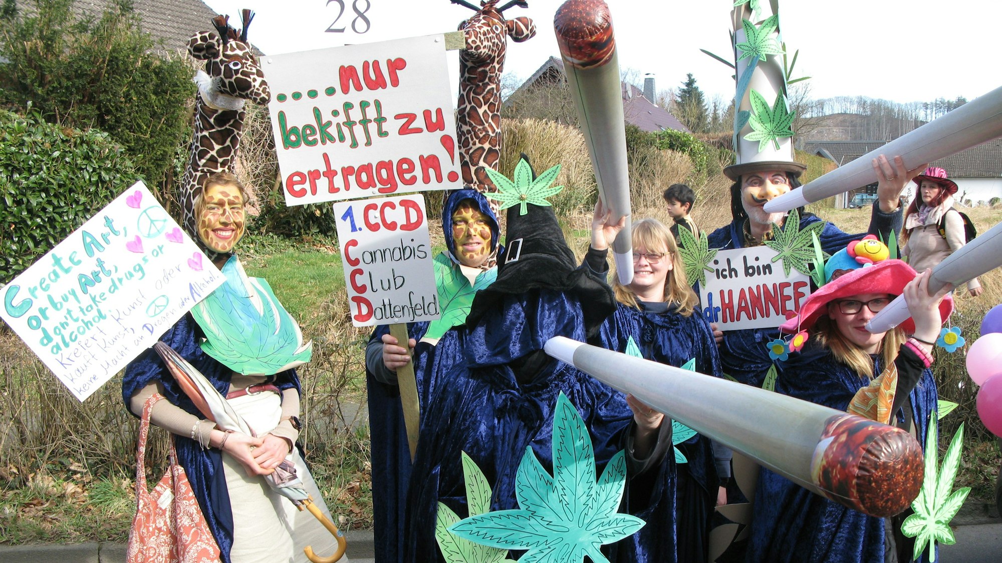 Sechs Personen in Kostümen mit Cannabis-Blättern und riesigen Joints.