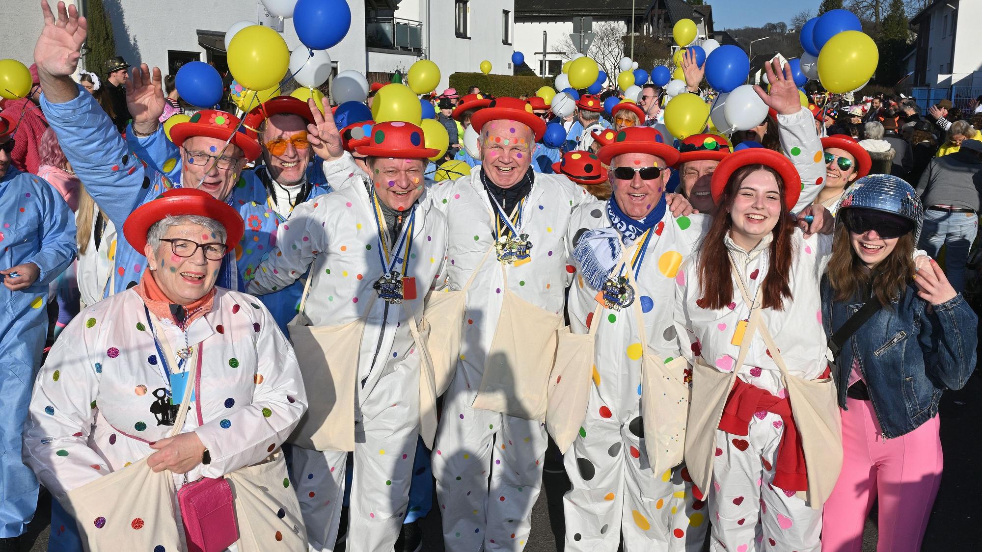 Eine bunt gekleidete Gruppe geht im Karnevalszug mit.