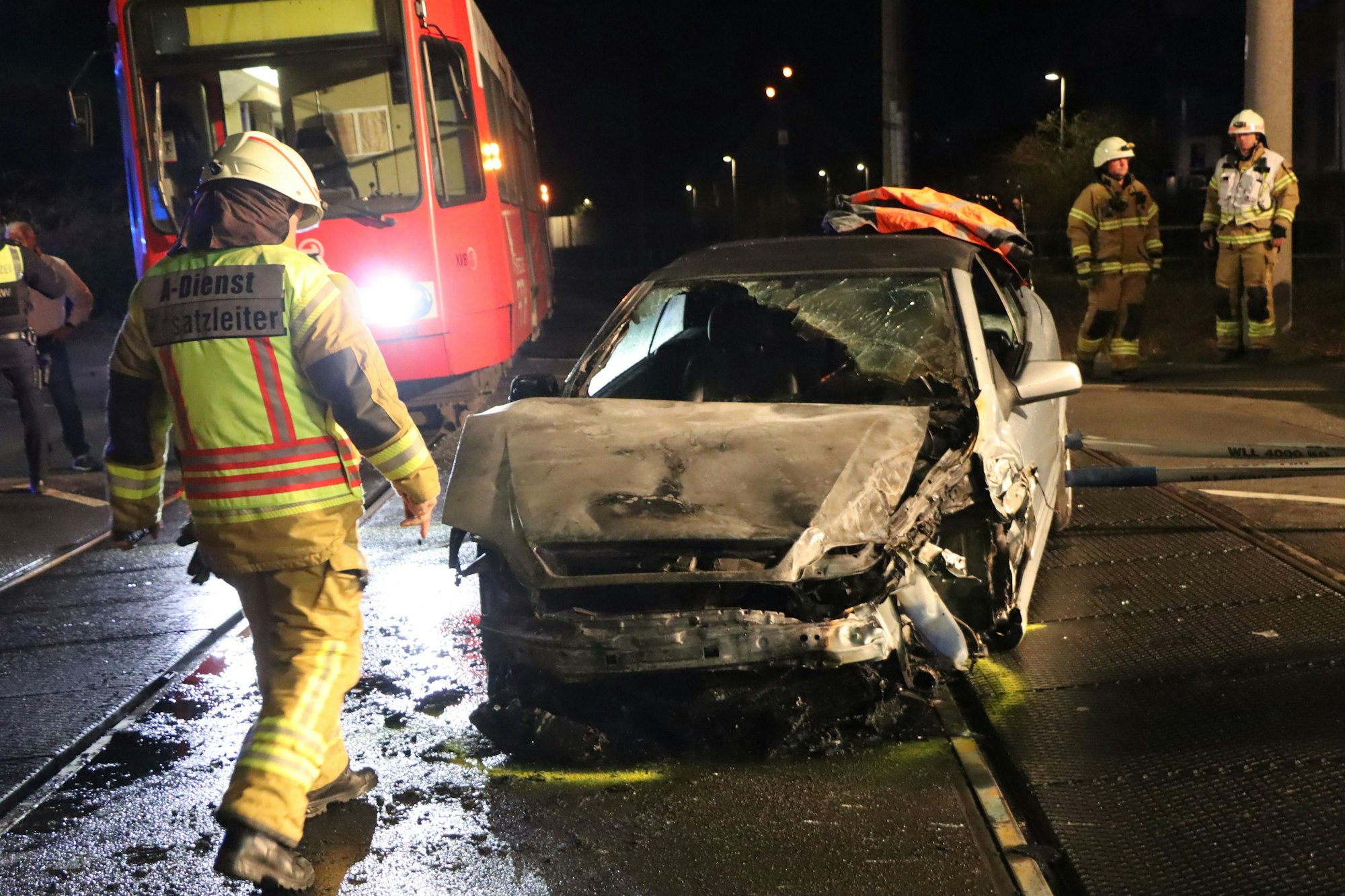 Das Bild zeigt Einsatzkräfte der Feuerwehr an einem ausgebrannten Auto.
