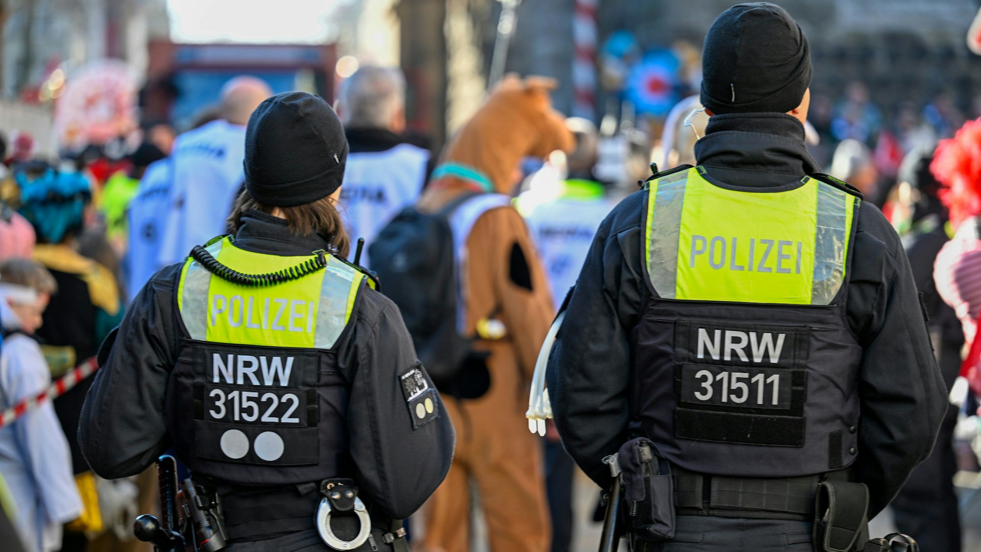 Zwei Polizisten sind am Rande eines Karnevalszuges zu sehen.