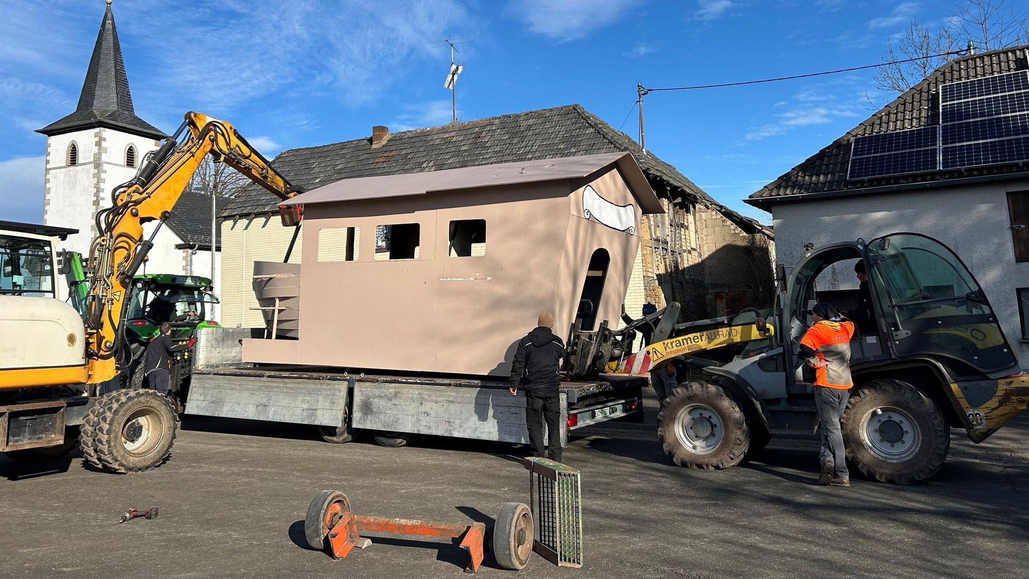 Ein Karnevalswagen wird in Nettersheim-Roderath mit Baggern auf einen neuen fahrbahren Untersatz gehoben.