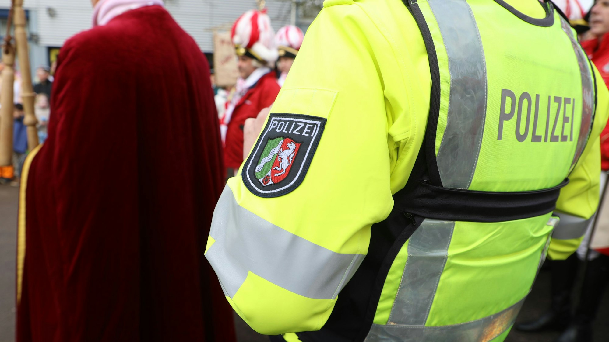 Ein Polizist steht am Rande einer Freiluft-Karnevalsveranstaltung in Bergisch Gladbach.