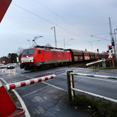 Das Bild zeigt einen Güterzug an einem Bahnübergang.