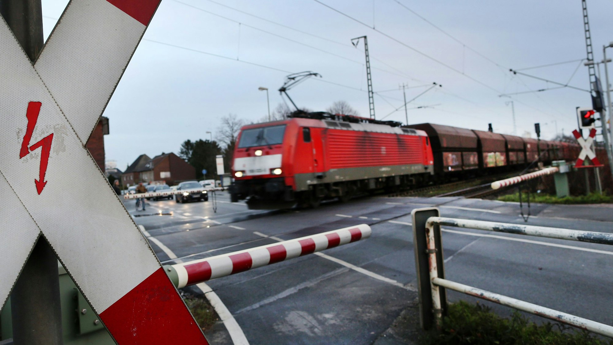 Das Bild zeigt einen Güterzug an einem Bahnübergang.