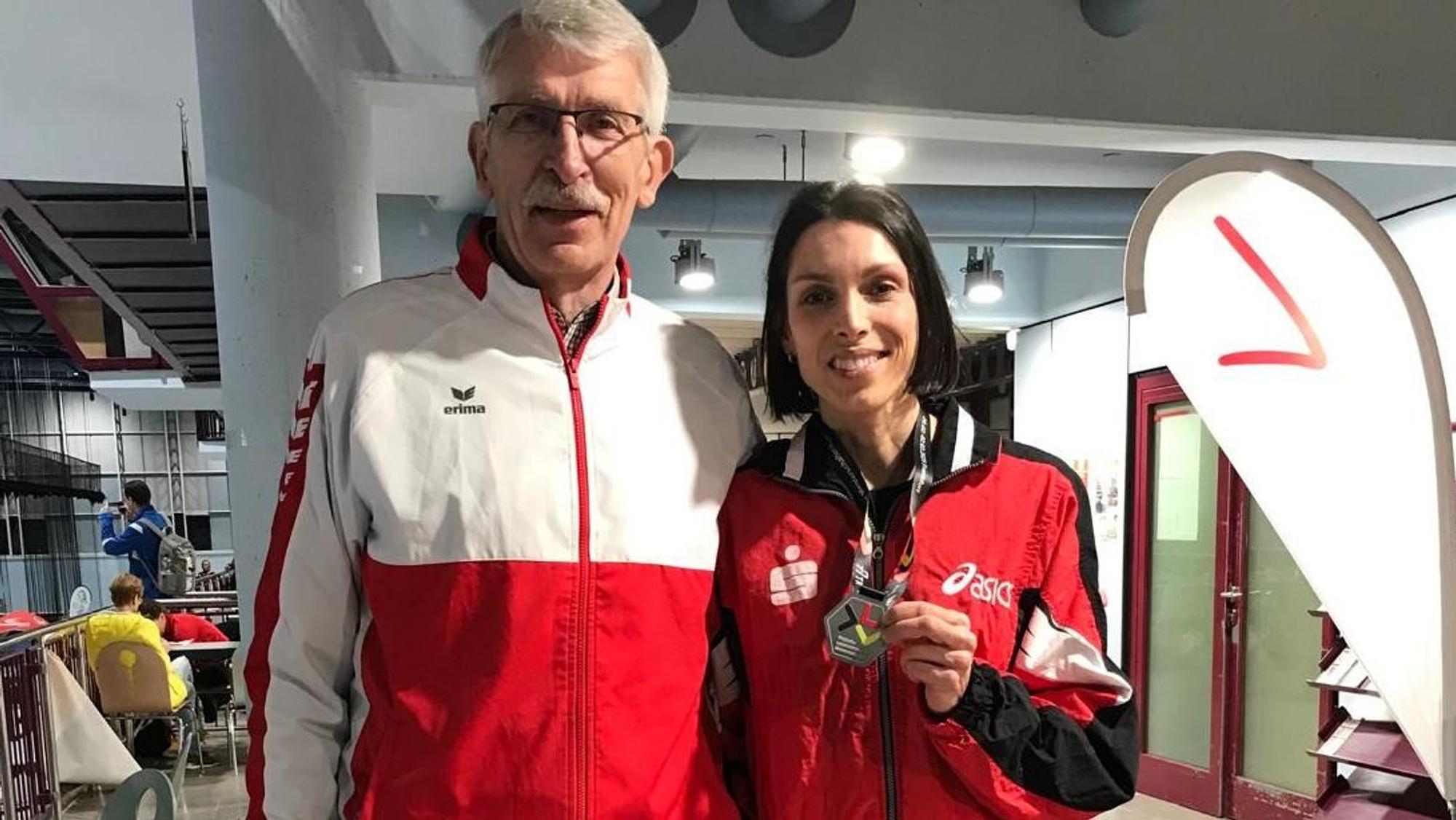 Das Foto zeigt Kristina Marten, die ihre Silbermedaille in die Kamera hält. Neben ihr steht der Teamchef.