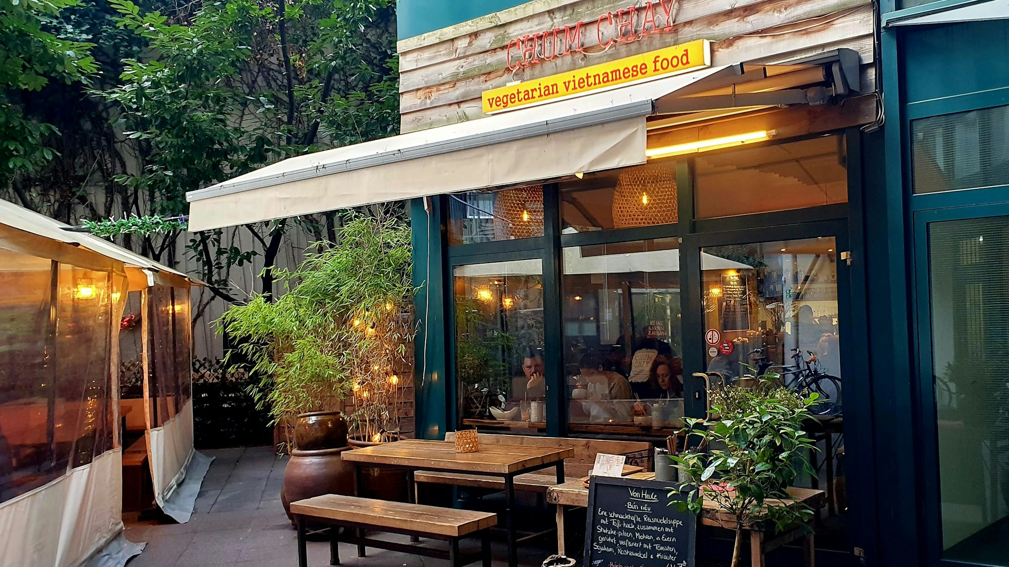 Das „Chum Chay“ von außen mit Pflanzen und Markise.