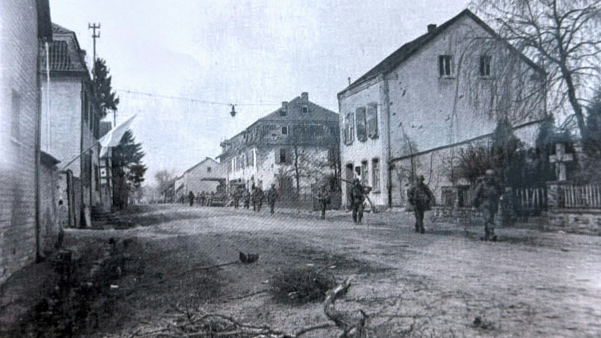 US-Soldaten gehen über eine Straße, die von Häusern gesäumt ist.