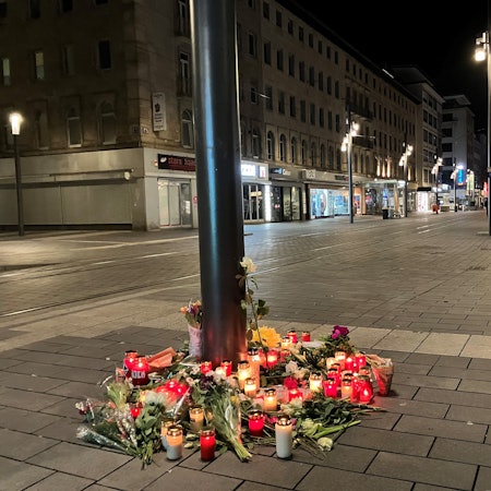 Das Bild zeigt Kerzen und Blumen, die in der Nähe des Paradeplatzes an einer Straßenbahn-Haltestelle in Mannheim zum Gedenken an die Opfer der Amokfahrt vom 03. März 2025 hingelegt wurden.