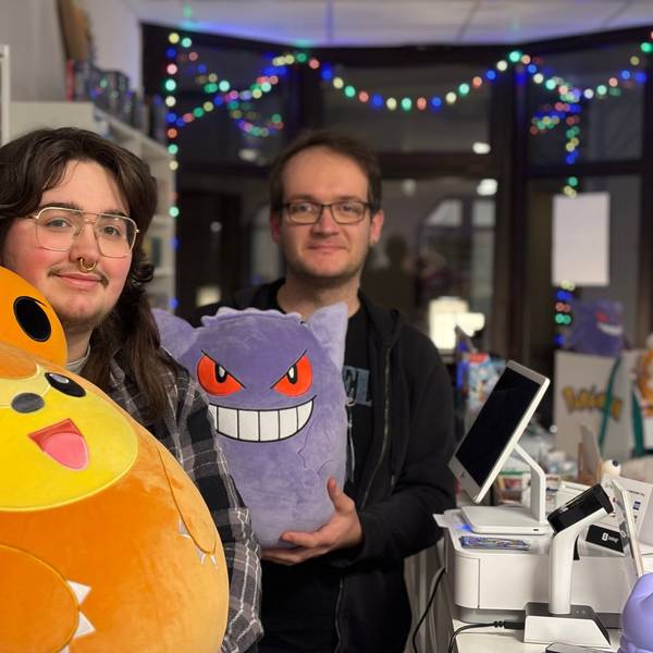 Zwei Männer mit Brillen halten Pokémon-Plüschfiguren in die Kamera.