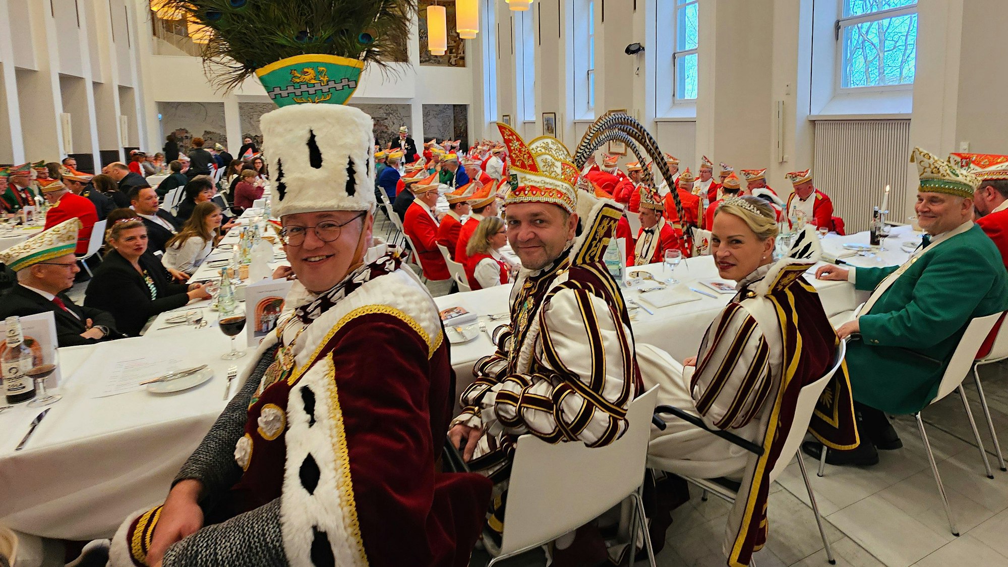 Bauer Michael, Prinz Christian I. und Jungfrau Steffi sitzen an einem Tisch beim Prinzenessen im Kardinal-Schulte-Haus.