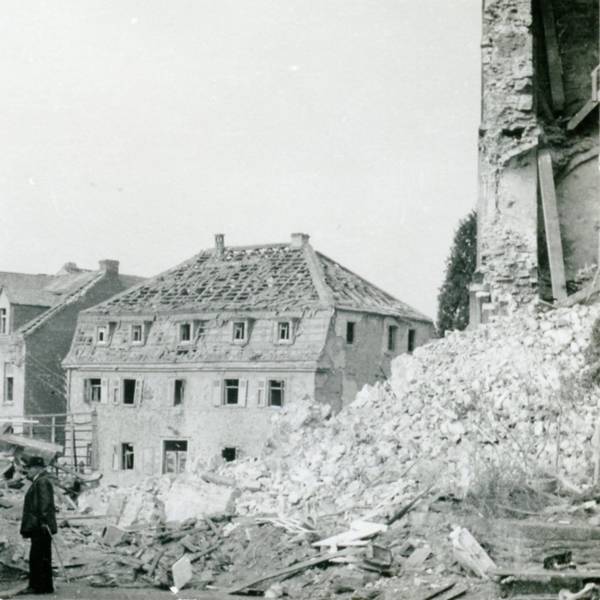 Zerbombte Häuser, Trümmer, ein Mann mit Stock, ein Haus ohne Dachpfannen.