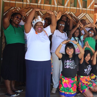 Frauen und Mädchen haben die Hände zu einem Dach über dem Kopf geformt.