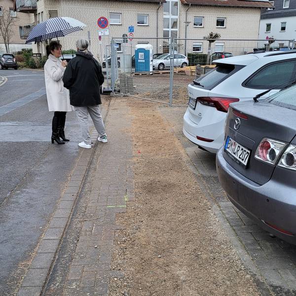 Ein Gehweg, dahinter ist ein Zaun zu sehen.