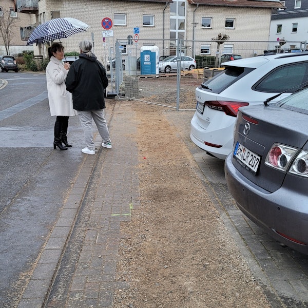 Ein Gehweg, dahinter ist ein Zaun zu sehen.