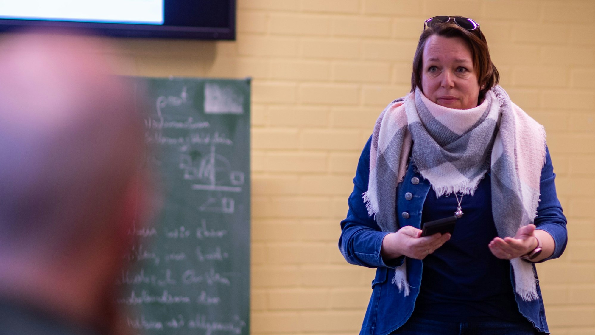 Melanie Houf steht neben einer Tafel in einem Klassenraum.