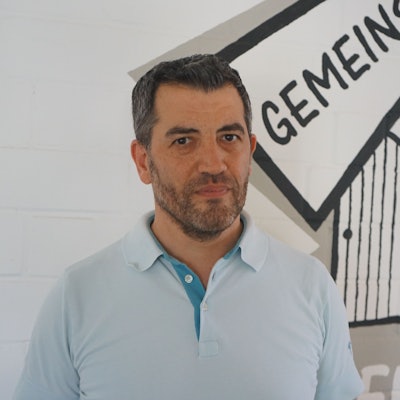 Auf dem Foto ist ein Mann in einem hellblauen Polohemd zu sehen. Er trägt einen Vollbart.