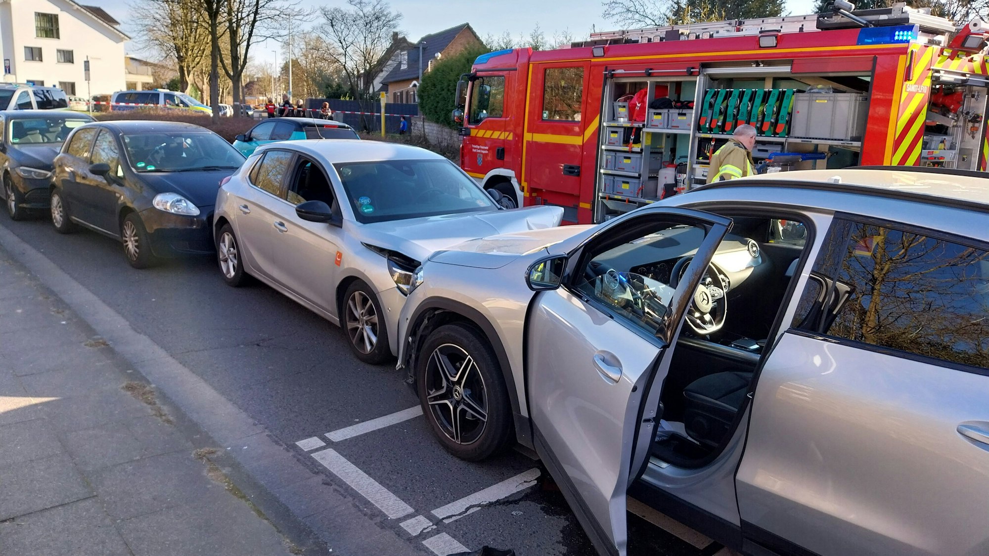 Aufeinander geprallte Autos an einer Unfallstelle. Im Hintergrund steht ein Fahrzeug der Feuerwehr.