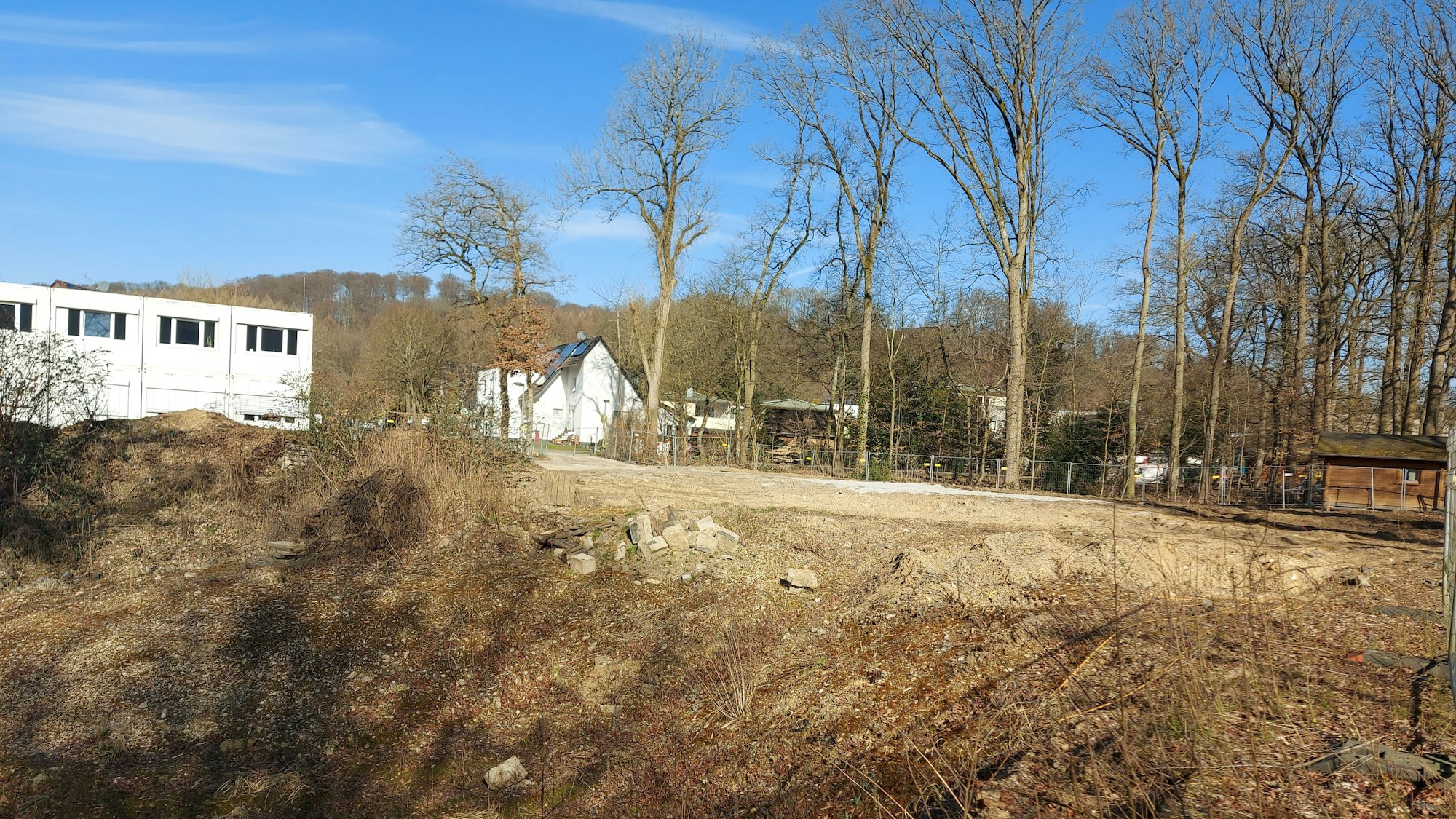 Eine Baugrube, dahinter ein Schulbau aus Containern.