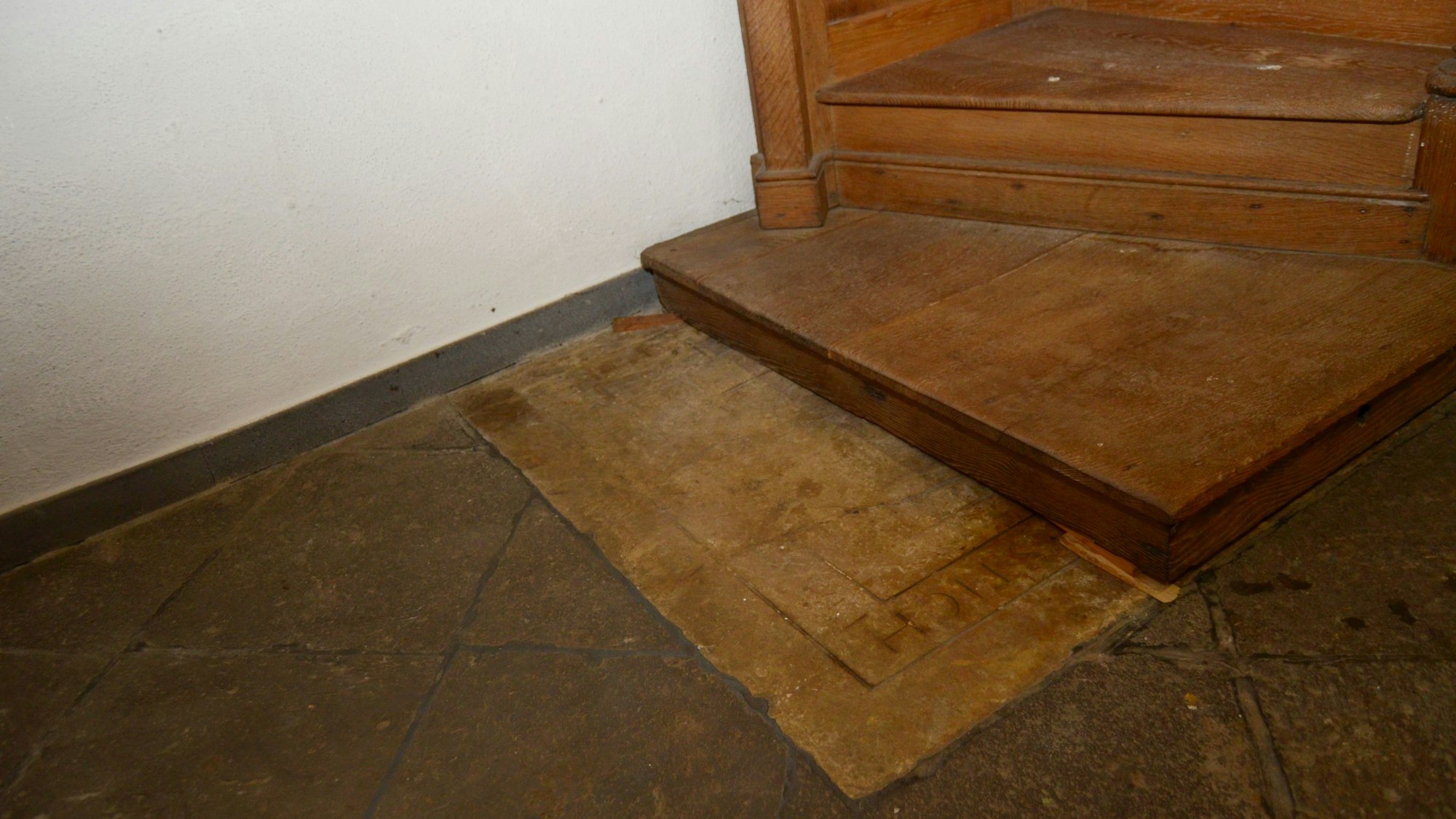 Der Boden des aus Holz gefertigten Beichtstuhls liegt auf der steinernen Platte.