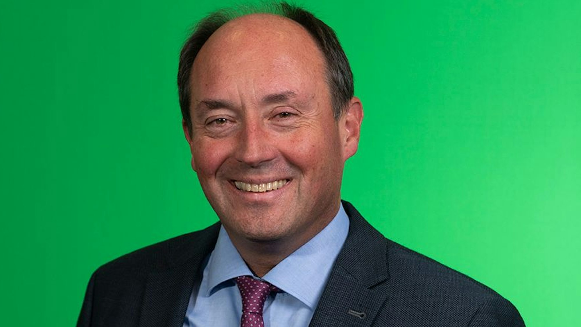 Ein Mann in dunklem Anzug mit blauem Hemd und Krawatte.