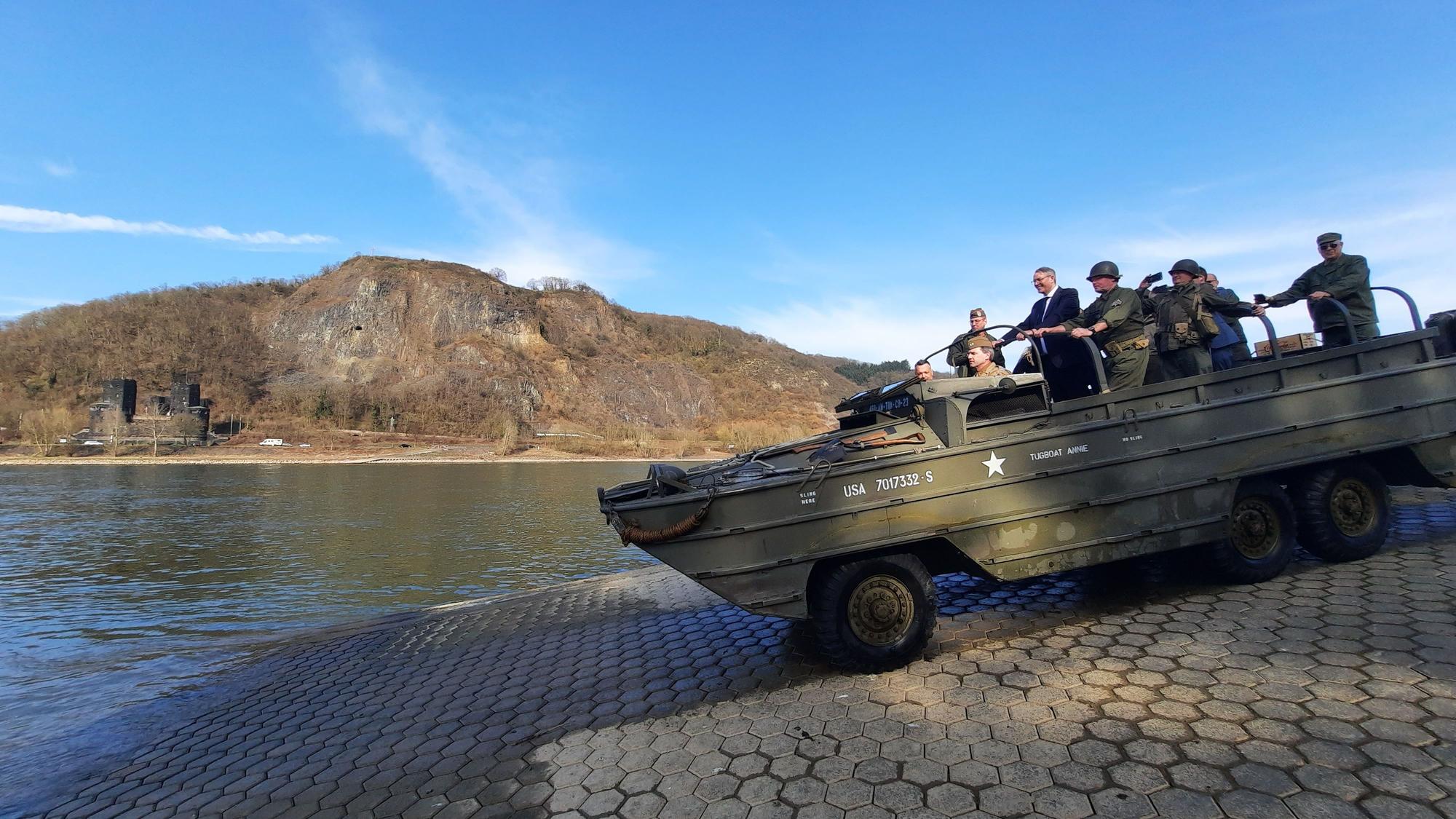 Ein historisches Militärfahrzeug fährt über eine Rampe auf den Rhein zu.