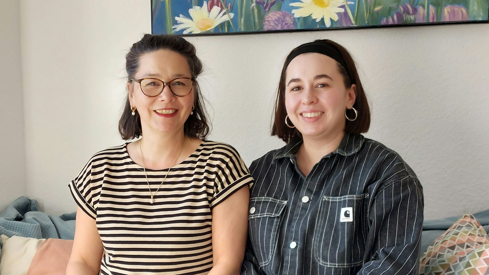 Zwei Frauen sitzen nebeneinander auf einem Sofa.