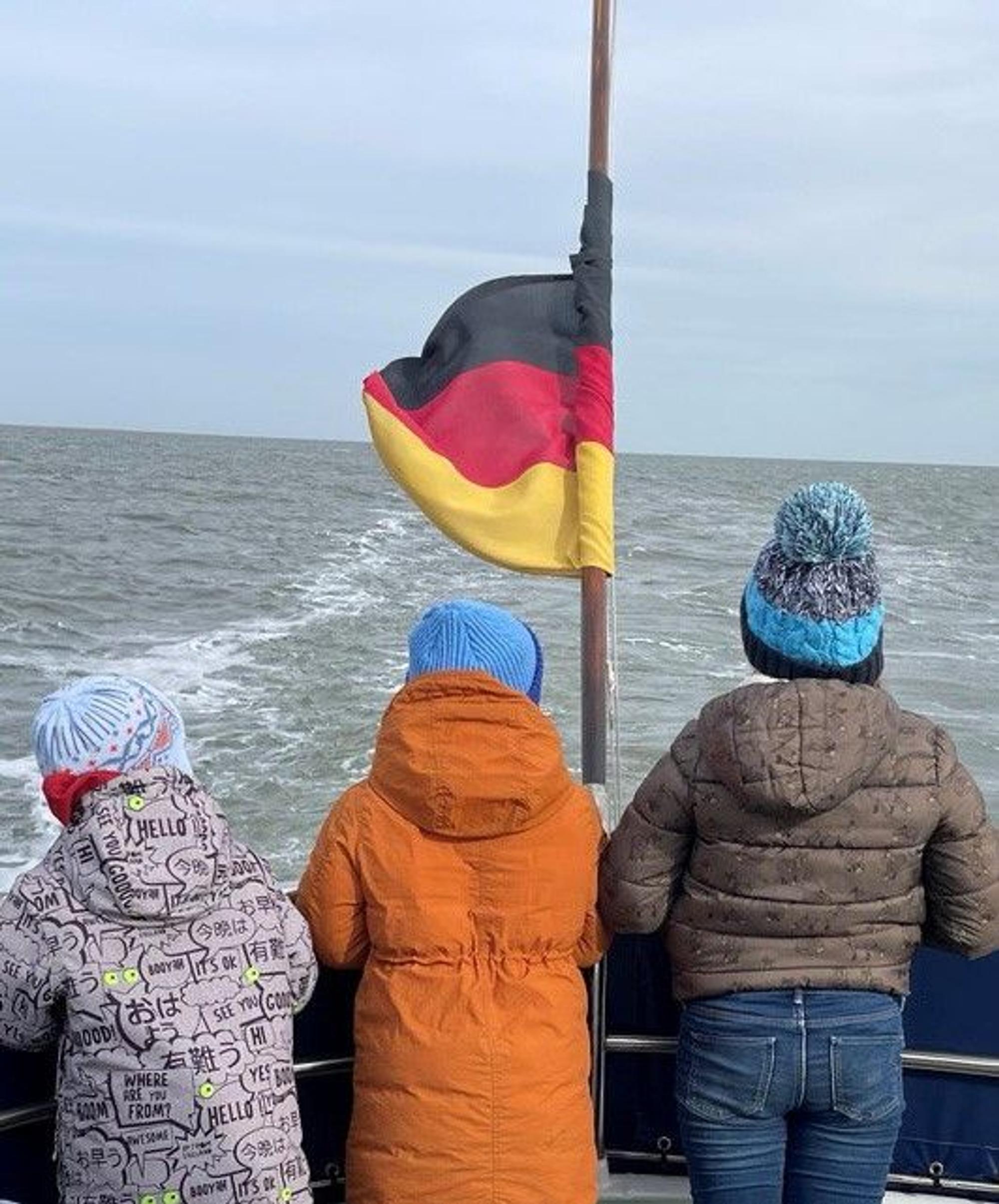 Auf dem Bild sind die drei kleinen Kinder von Olesia S. von hinten bei der Seebestattung ihrer Mutter zu sehen.