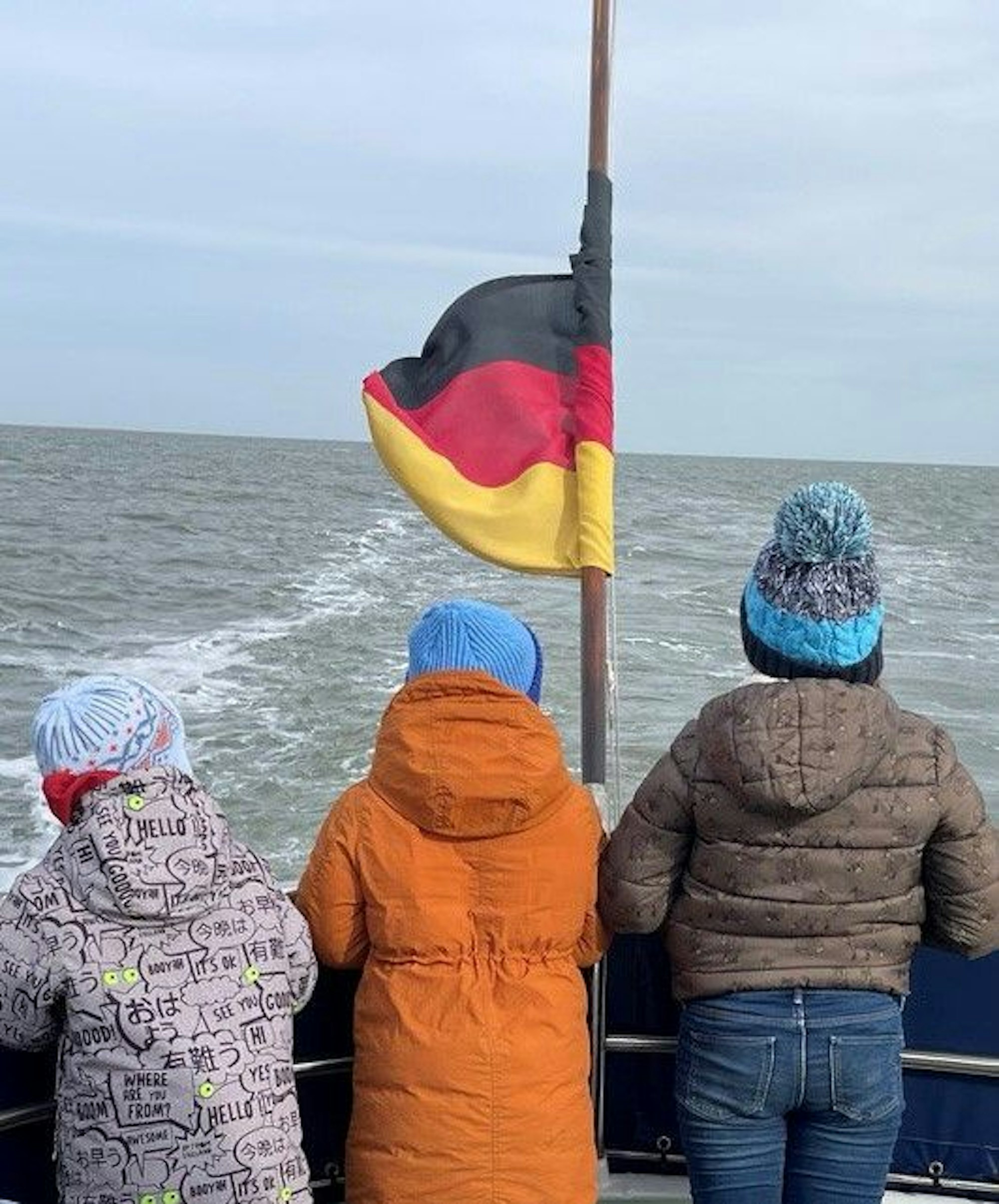 Auf dem Bild sind die drei kleinen Kinder von Olesia S. von hinten bei der Seebestattung ihrer Mutter zu sehen.