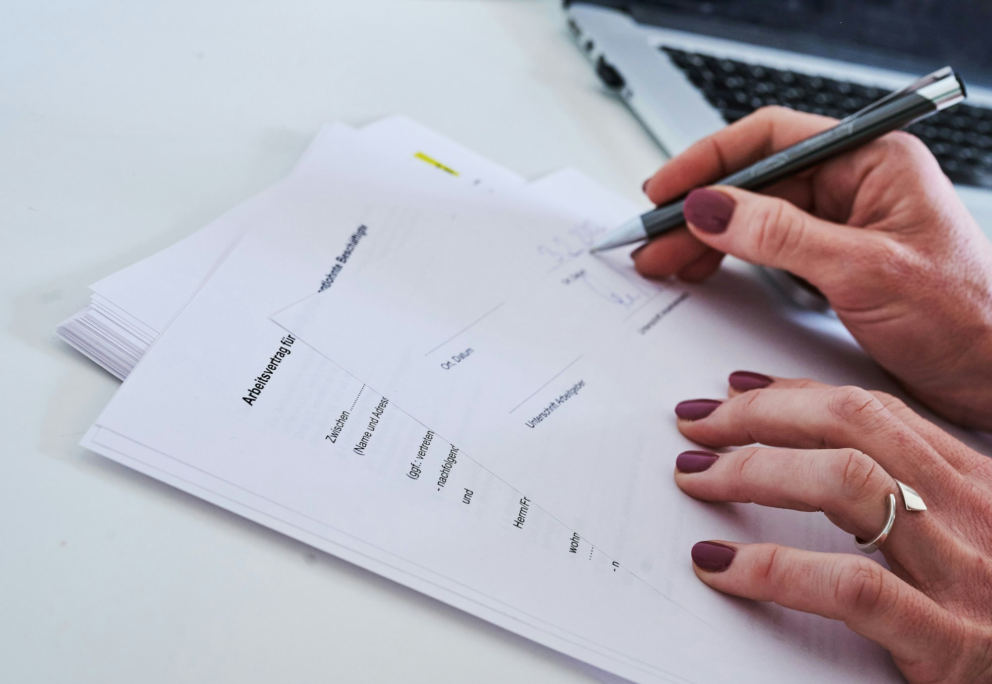 Das Bild zeigt eine Frauenhand,die einen Arbeitsvertrag unterschreibt.