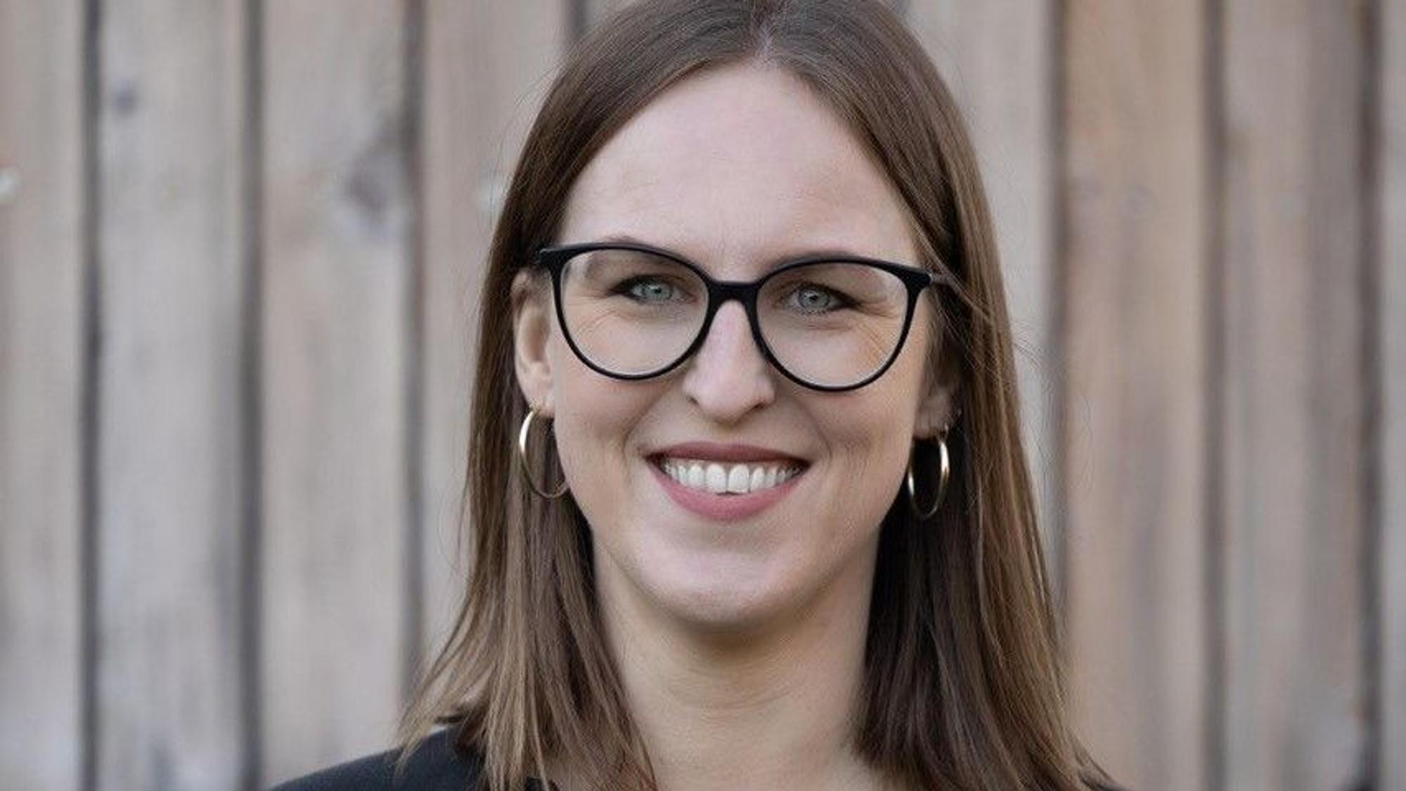 Hannah Schiefer steht vor einer Wand und lächelt.