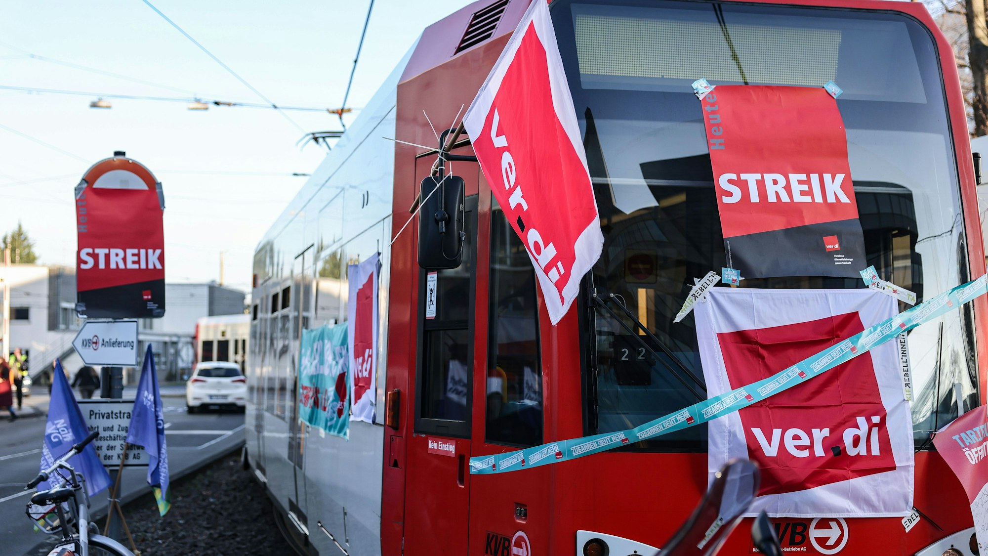 Eine mit Streik-Plakaten beklebte Straßenbahn der Kölner Verkehrs-Betriebe (KVB) steht vor dem Bahndepot. (Archivbild)