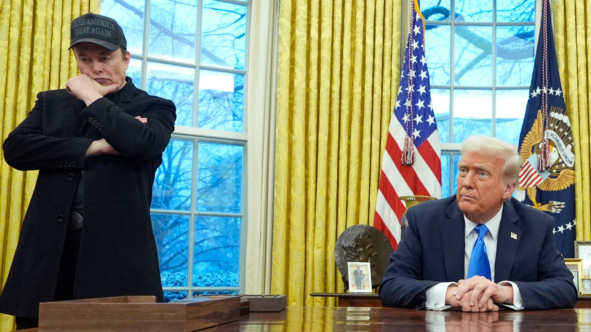 Elon Musk (l) hört zu, während US-Präsident Donald Trump mit Reportern im Oval Office im Weißen Haus spricht.