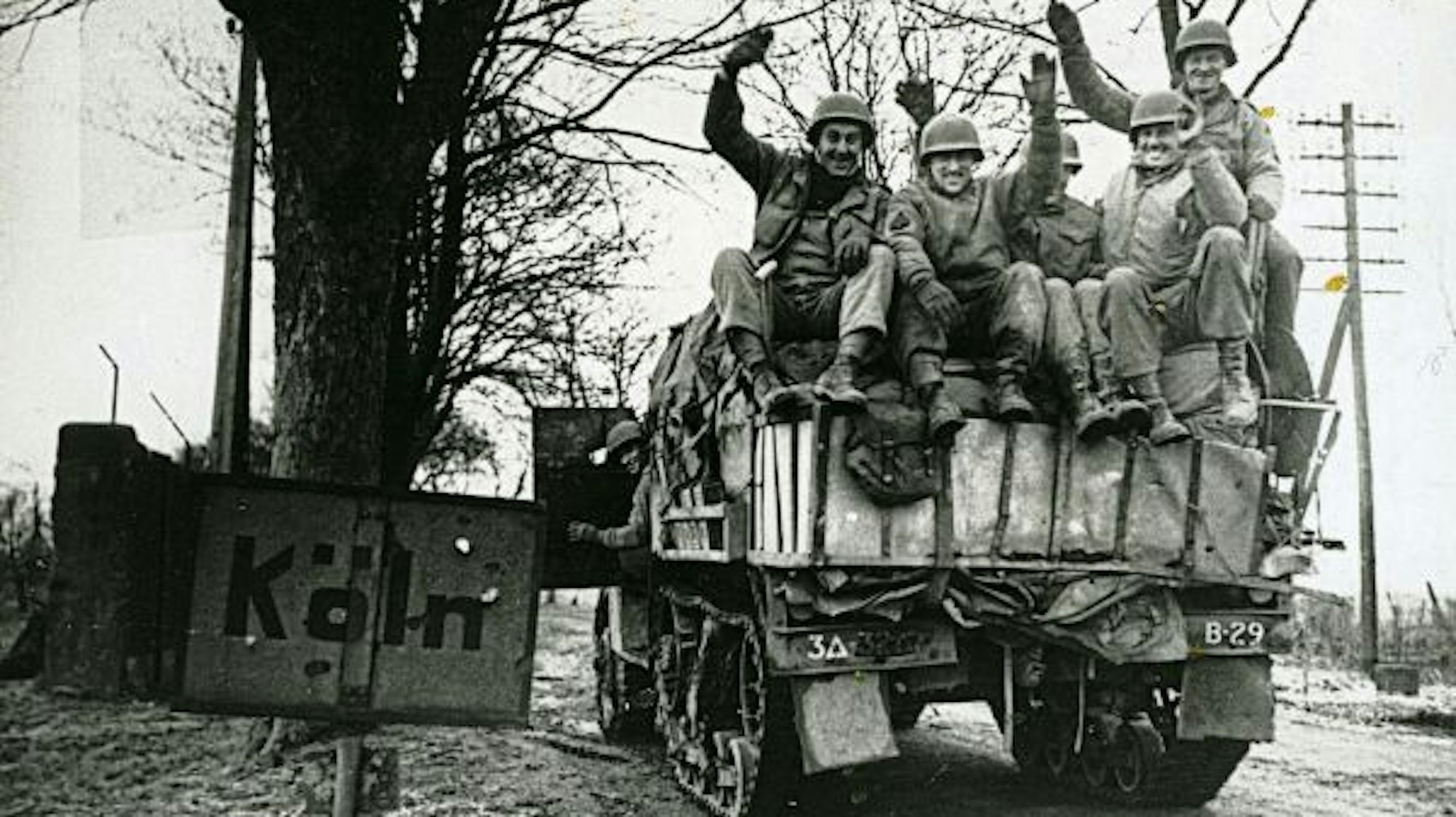 Panzer mit US-Streitkräften passiert ein Ortsschild von Köln.