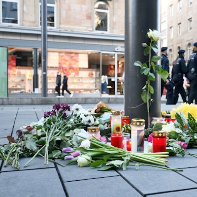 Das Bild zeigt Kerzen und Blumen, die in der Nähe des Paradeplatzes an einer Straßenbahnhaltestelle in Mannheim in Gedenken an die Opfer der Amokfahrt vom Rosenmontag liegen.