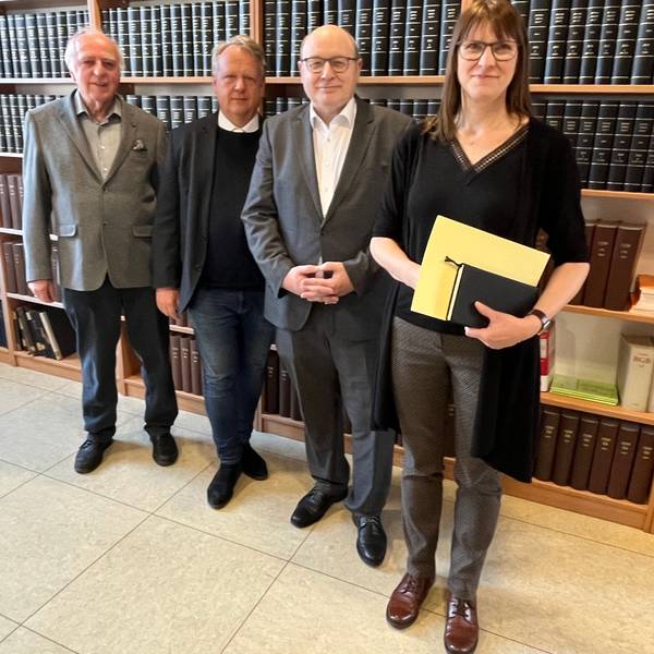 Vier Menschen vor Bücherwand